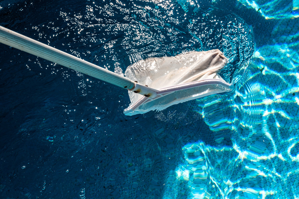 An Aquia technician skimming a sparkling clean San Antonio pool.